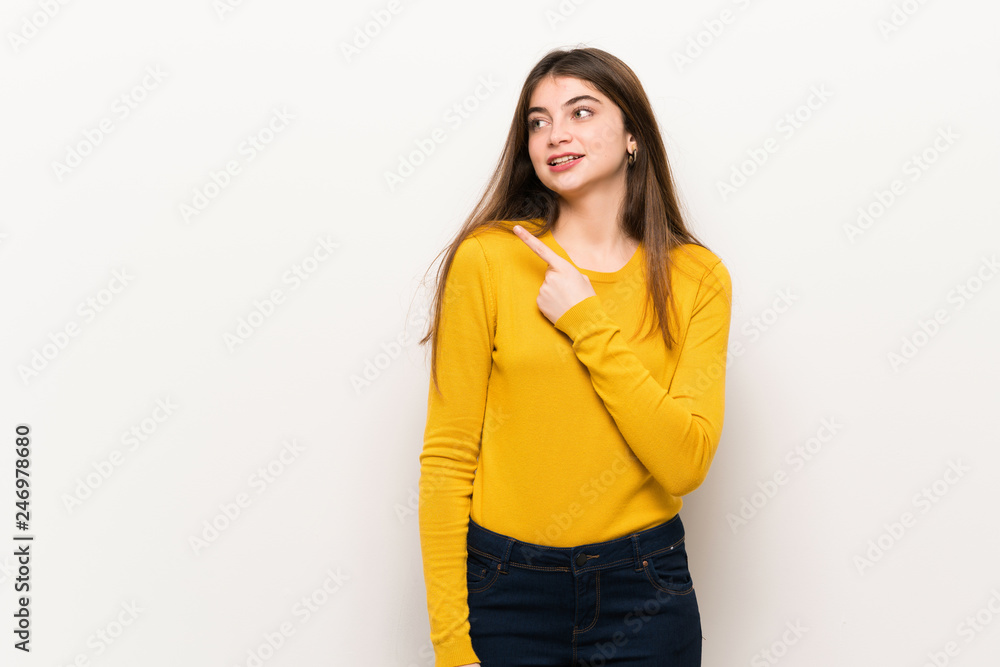 Young woman with yellow sweater pointing to the side to present a product Young woman with yellow sweater pointing to the side to present a product