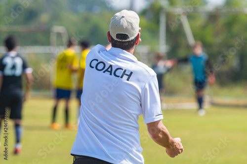 Back of sport coach wearing COACH shirt at an outdoor sport field