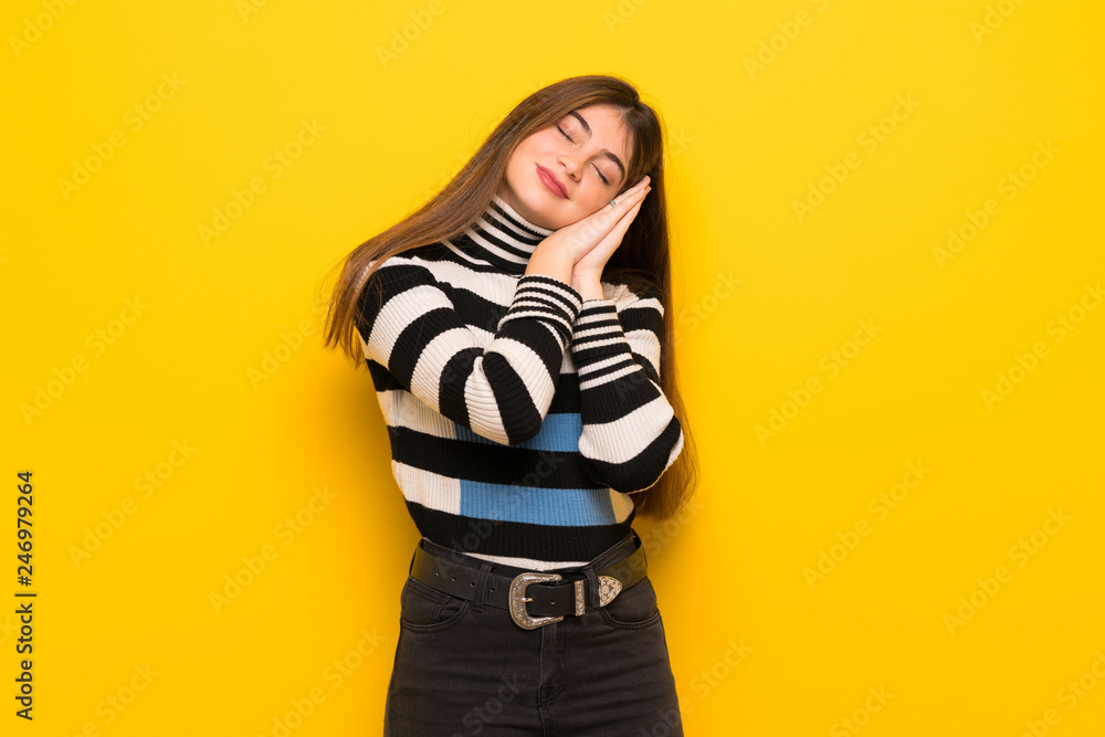 Young woman over yellow wall making sleep gesture in dorable expression Young woman over yellow wall making sleep gesture in dorable expression
