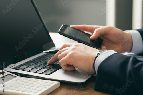 young businessman in office with smartphone tablet at workplace