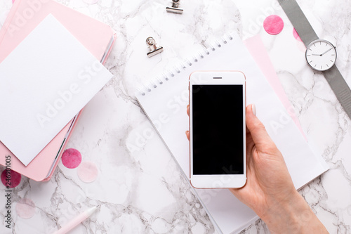 Female hand with mobile phone on marble background in office