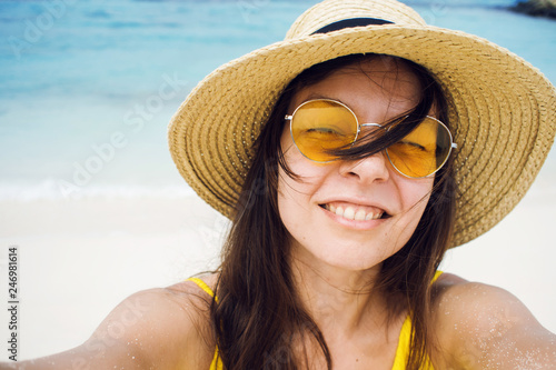 Happy girl on vacation. Young brunette in a straw hat and sunglasses, taking a selfie