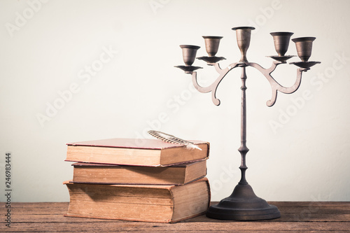 Wall Mural still photography : stack of old book with feather pen and candelabrum on old wo