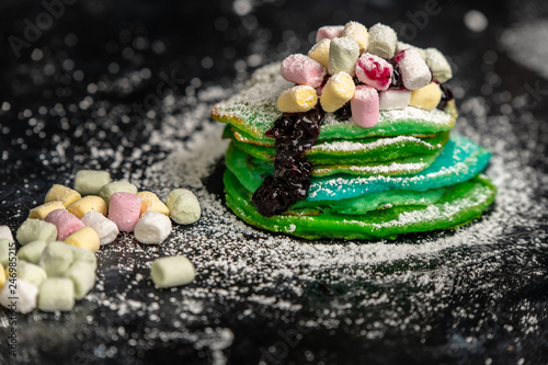 green and blue pancakes are sprinkled with powdered sugar and colored marshmallows
