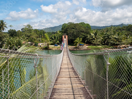 Pedestrian hanging bridge over river in tropical forest, Bohol, Philippines. November, 2018 photo