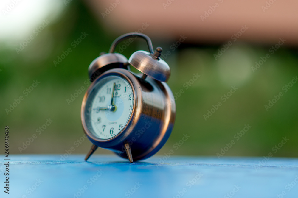 Golden alarm clock picture placed on a blue table, green background Punctual concept With copy space Golden alarm clock picture placed on a blue table, green background Punctual concept With copy space