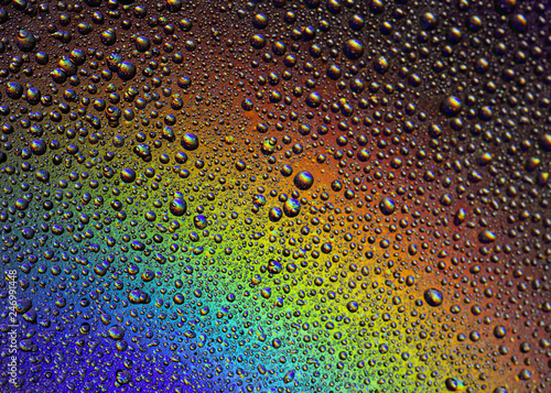 Drops of water on the glass  with the reflection of the rainbow.