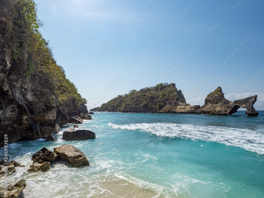 Exotic destination background with tuquoise sea water, palm trees, white sand beach and golden sun light. Warm natural colours. Top view. Atuh beach, Nusa Penida Island, Bali, Indonesia. October, 2018