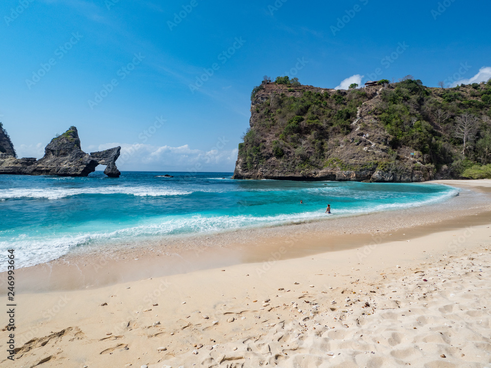 Exotic destination background with tuquoise sea water, palm trees, white sand beach and golden sun light. Warm natural colours. Top view. Atuh beach, Nusa Penida Island, Bali, Indonesia. October, 2018