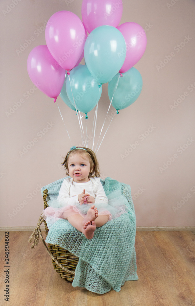 Fototapeta premium Little baby sitting in a basket with balls.