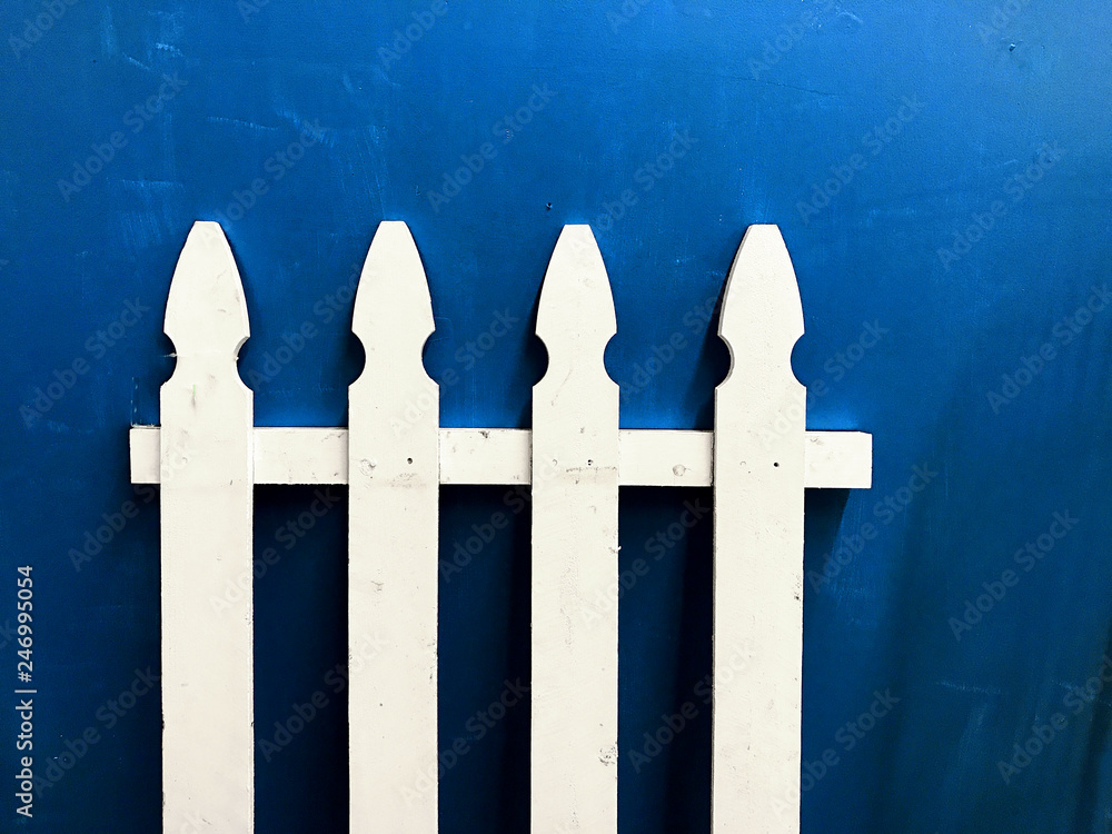 Detail of white picket fence on blue background