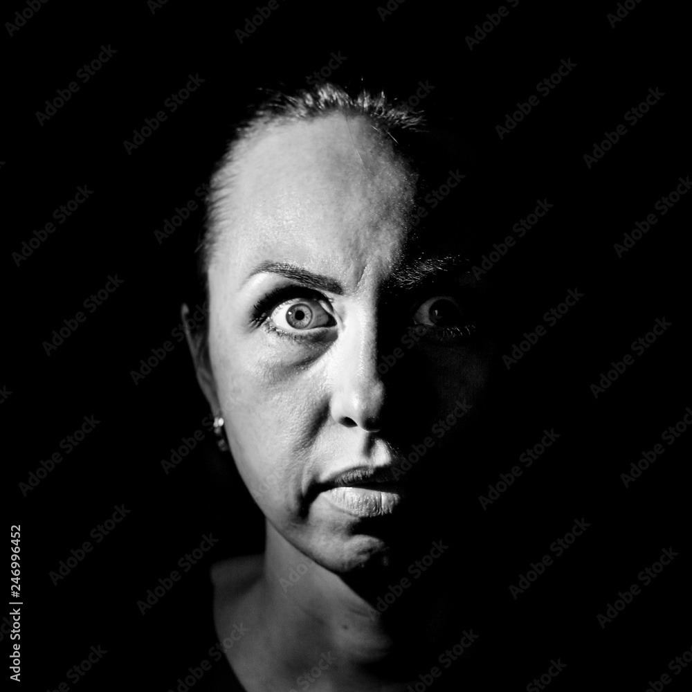 Portrait of a scared or surprised caucasian woman. Scary and fear concept. Black and white shot, low key lighting. Isolated on black. Portrait of a scared or surprised caucasian woman. Scary and fear concept. Black and white shot, low key lighting. Isolated on black.