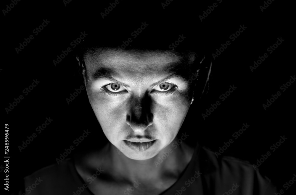 Fototapeta premium Stylish portrait of a attractive caucasian woman who carefully looks directly to watcher. Black and white shot, low-key lighting. Isolated on black.