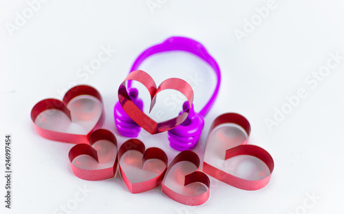 Ribbons shaped as hearts on top plastic hand on white background, valentine day concept