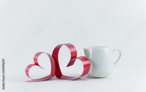 Ribbons shaped as hearts be side cup on white background, valentine day concept.