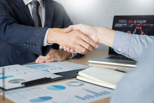 shaking Hand between businessman of cooperation over Stock market chart, business trading concept