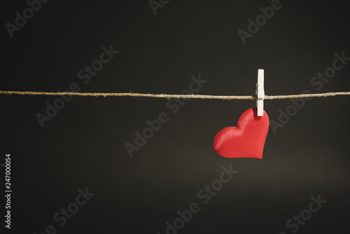 A single lonely red heart hanging from a string by white clothes peg. Romantic Valentine's Day scene with copy space. © Ana Fidalgo