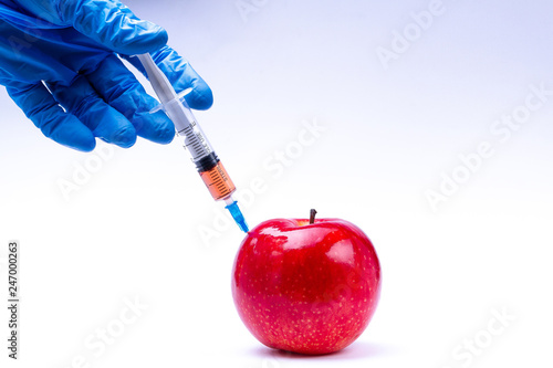Pesticides and nitrates are injected into a red apple with a syringe. Gmo concept and genetically modified organism. Gmo free and natural fruits without chemical additives. photo