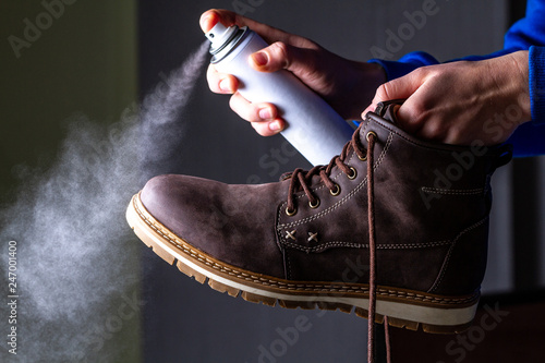 Foto A person is cleaning and spraying agent on men's suede casual boots for protection from moisture and dirt