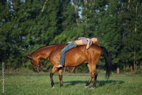 Beautiful cowgirl bareback ride her horse in woods glade at sunset 