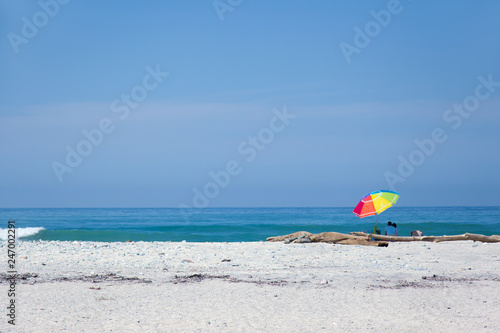 Paar sitzt am Strand unter einem Sonnenschirm