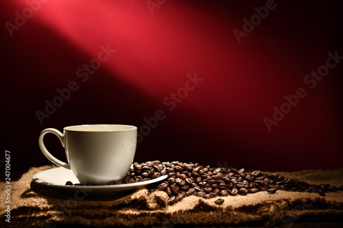 Cup of coffee and coffee beans on reddish brown background