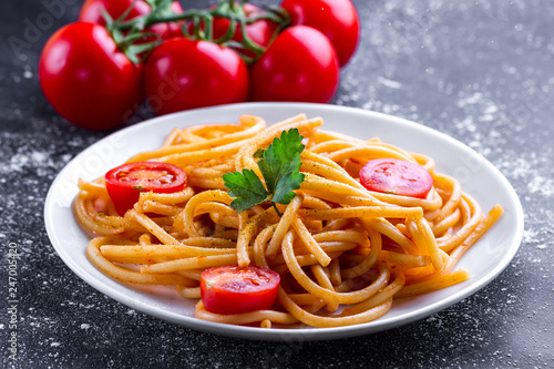 Delicious, homemade pasta with tomato sauce, parsley and fresh vegetables on a plate. Italian food