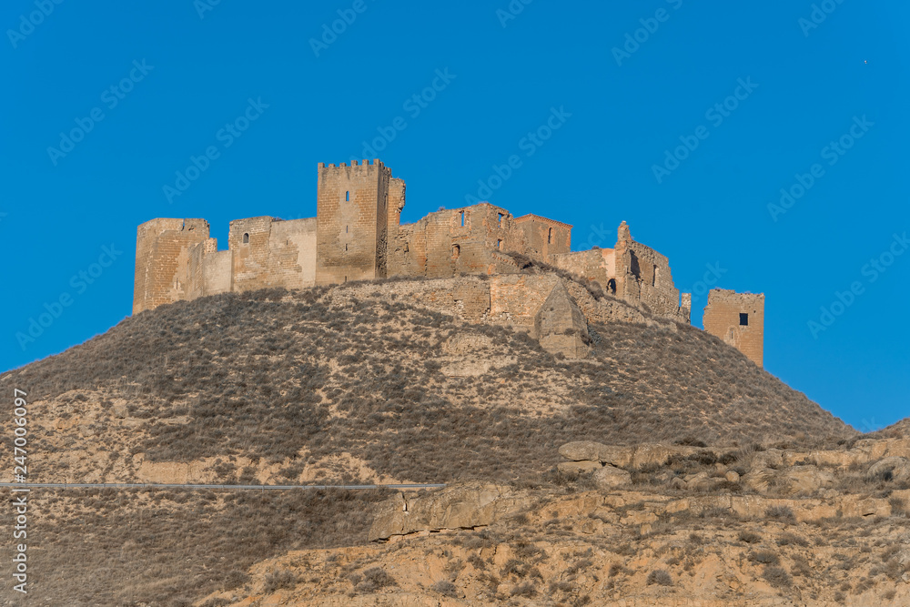 Aerial view of the ruined medieval abandoned Montearagon castle, namesake of the famous kingdom on a bare mountain top near Huesca, Aragon province Spain with blue sky