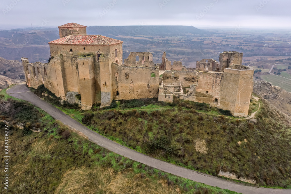 Aerial view of the ruined medieval abandoned Montearagon castle, namesake of the famous kingdom on a bare mountain top near Huesca, Aragon province Spain with stormy cloudy sky
