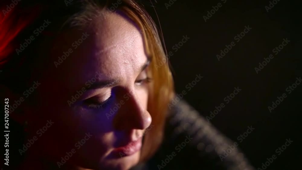 adult woman is touching her hair and rising eyes to camera in dark room with red illumination adult woman is touching her hair and rising eyes to camera in dark room with red illumination