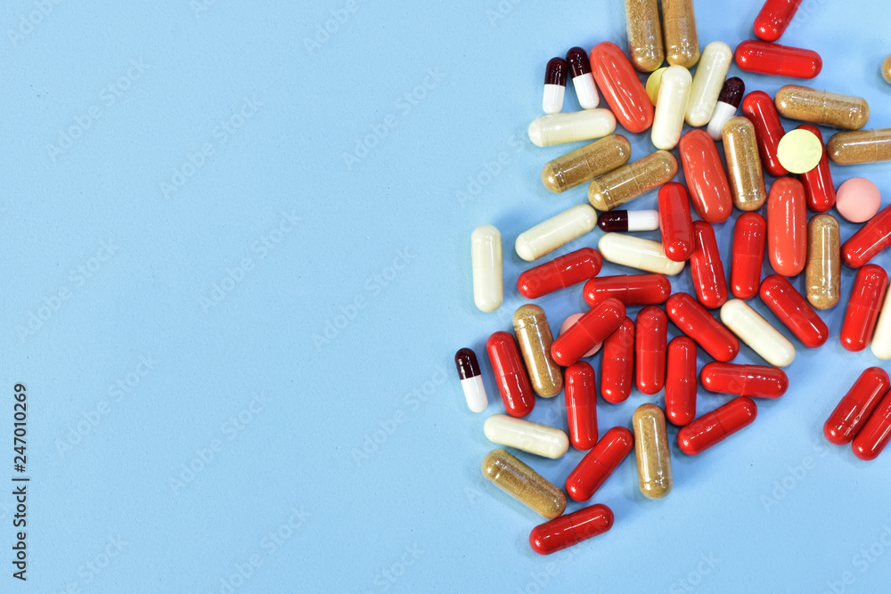 High doses of medicine for treatment. pain medication tablets. Assorted pharmaceutical medicine pills, tablets and capsules over blue background High doses of medicine for treatment. pain medication tablets. Assorted pharmaceutical medicine pills, tablets and capsules over blue background