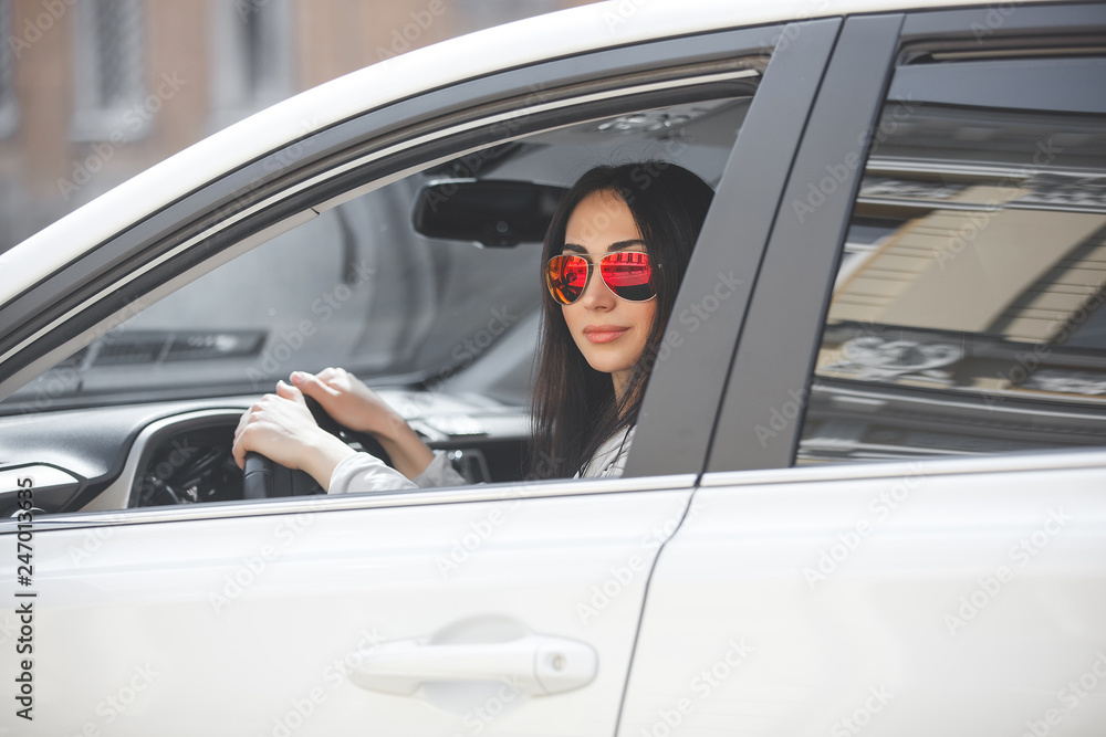 Naklejka premium Confident woman in automobile. Lady driving a car. Young beautiful female sitting in the auto. Urban woman.