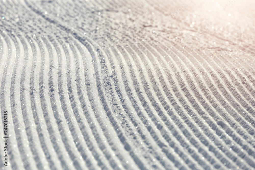 Close-up ski piste, ski slope, Abstract background with tracks on the snow, newly groomed snow Close-up ski piste, ski slope, Abstract background with tracks on the snow, newly groomed snow