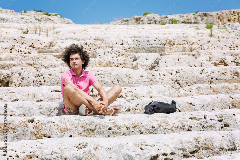 A young man sits on the steps of the amphitheater A young man sits on the steps of the amphitheater