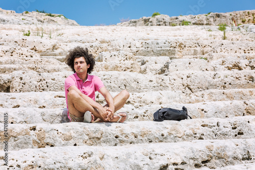 A young man sits on the steps of the amphitheater