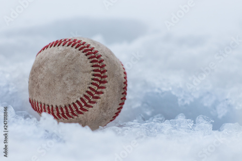 Baseball stuck in snow and ice during winter. Baseball spring training.