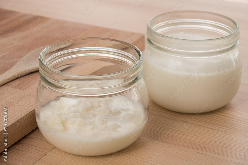 Organic Kefir and kefir grains in glass jars with wooden board and spoon Organic Kefir and kefir grains in glass jars with wooden board and spoon