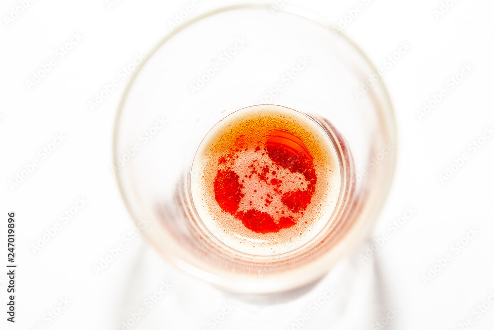 Wheat-colored beer in a glass transparent glass is left on the bottom with a small foam on the surface, the drink absorbs thirst in the summer, is popular at parties. Wheat-colored beer in a glass transparent glass is left on the bottom with a small foam on the surface, the drink absorbs thirst in the summer, is popular at parties.