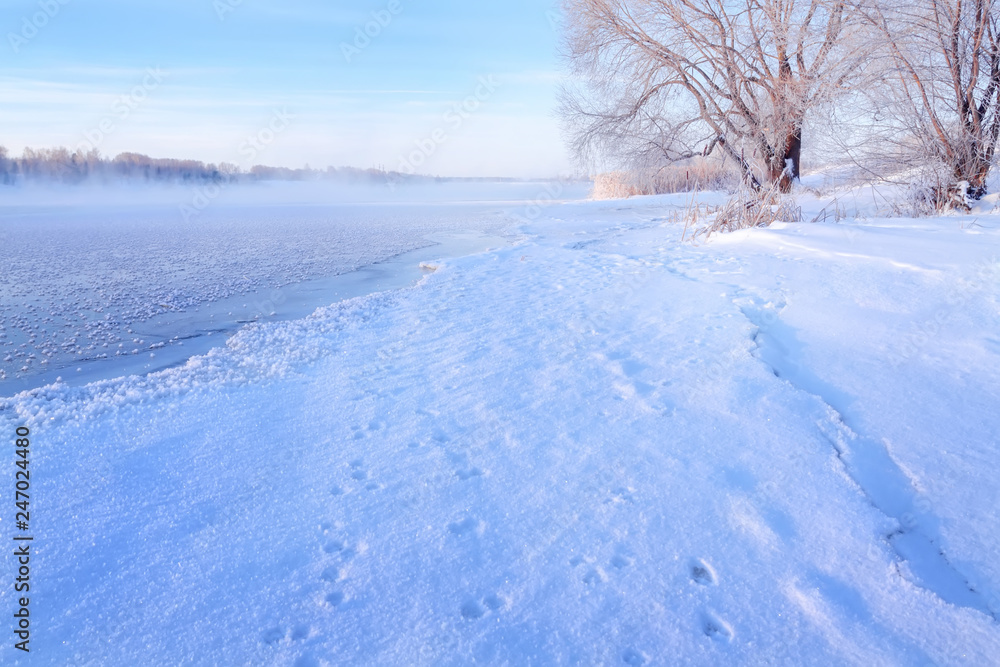 Winter landscape in the early morning overlooking the banks of the Volga River. Frosty fog obscures the banks of the river. The tops of the trees are covered with hoarfrost. Winter landscape in the early morning overlooking the banks of the Volga River. Frosty fog obscures the banks of the river. The tops of the trees are covered with hoarfrost.