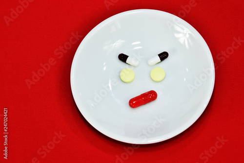 Sad face made of medicine. pain medication tablets. colored pills on porcelain dish. Assorted pharmaceutical pills.
