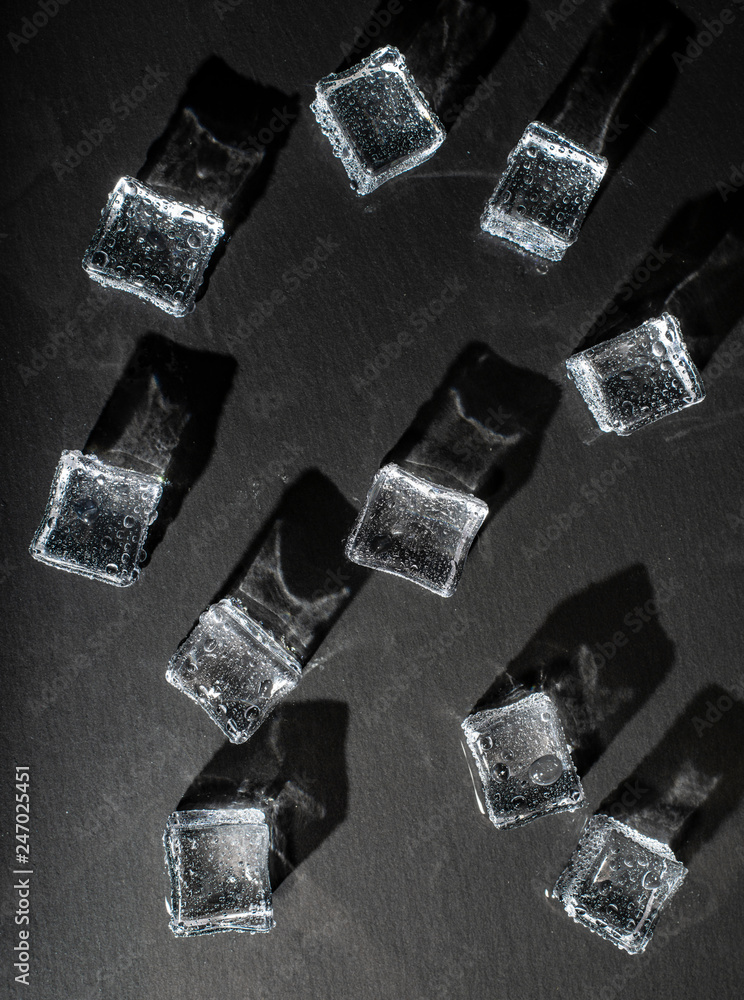 Ice cubes on black stone board. Hard light. Deep shadows. Cold and freshness concept. Ice cubes on black stone board. Hard light. Deep shadows. Cold and freshness concept.