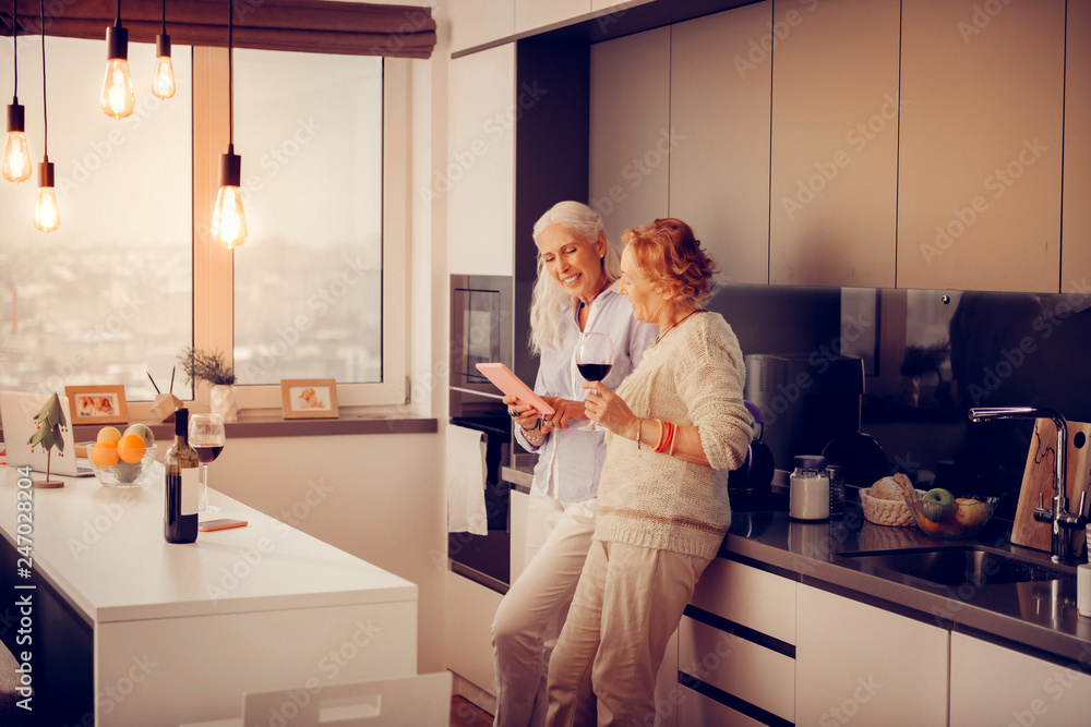 Positive elderly women surfing the Internet together Positive elderly women surfing the Internet together