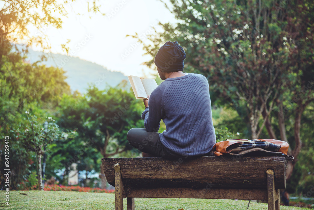 The young man travels nature on the mountain, is sitting and relaxing, reading a book in the flower garden. The young man travels nature on the mountain, is sitting and relaxing, reading a book in the flower garden.