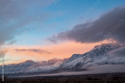 pink sky clouds over snowy mountain range at sunrise