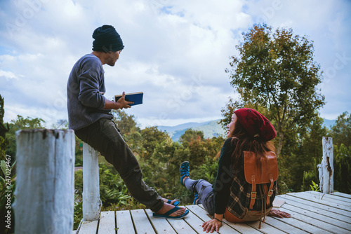 couple lover natural travel on the mountain, sitting relax reading books in the midst of nature on the white wooden bridge. photo