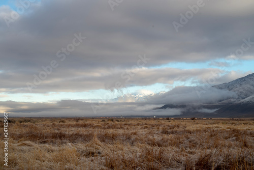 winter landscape brown grass desert valley clouds over mountain range
