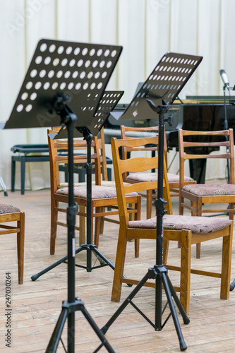 Empty seats and some instruments in music hall awaiting orchestra to come on the stage. black music stand on stage.