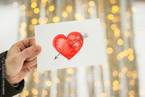 white card with a red heart drawn pierced arrow on a beautiful winter background photo