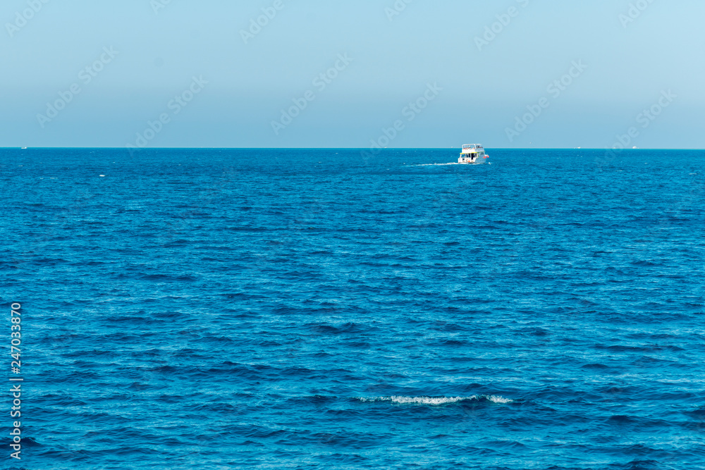 Obraz premium Tourist ship sailing in ocean. shipping business tourism concept. Background. Blue sea, pink sky at dawn and a white ship on the horizon. Concept of rest, vacation, weekend and cruise.