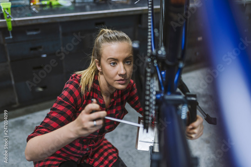 Woman bicycle engineer is repairing a bike in the workshop. Bicycle mechanic in a workshop in the repair process. Technical expertise taking care Bicycle Shop